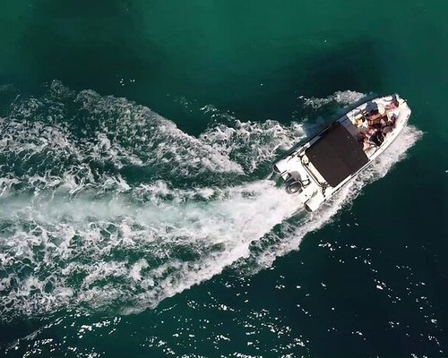 Draw a realistic photo of a speedboat with a sunset in the background