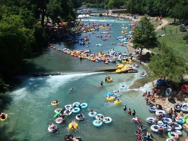 Dozens of people riding colorful inner tubes down river