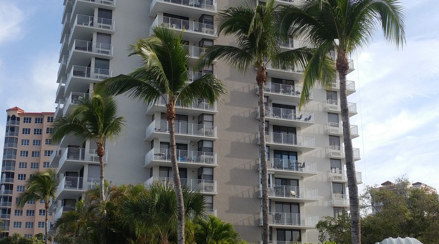 Building pix from private beach. #1108 is 3rd balcony down from top, visible  just above palm branch on last tree.