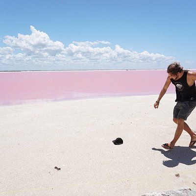 A man grabbing his hat at the pink lake at Las Coloradas