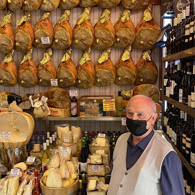 Un homme âgé se tient devant l'étalage de viandes et de fromages