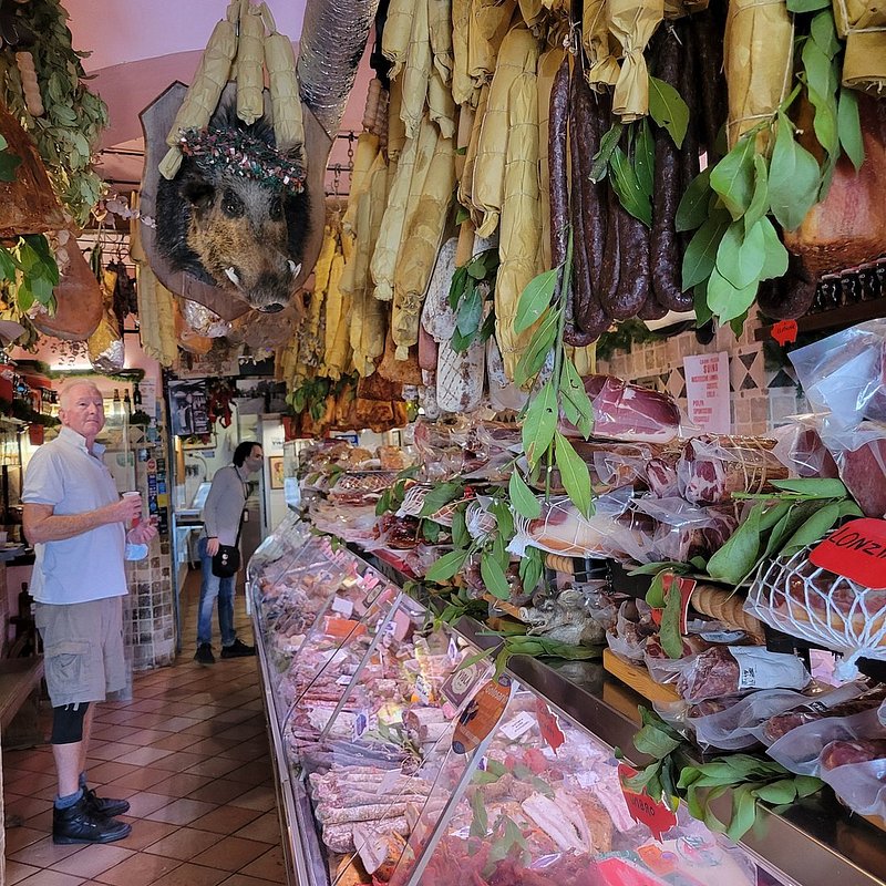 An elderly man checking out the food on display in a meat shop in Rome