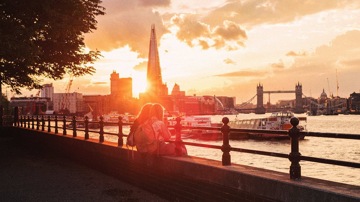 A couple sitting on a dock in London at sunset