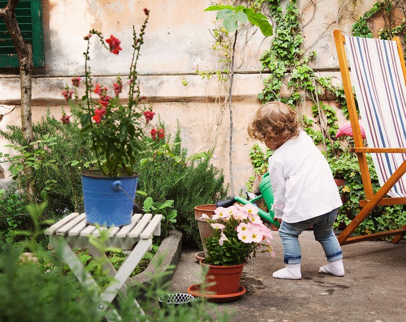 A toddler watering plants in a garden in Rome