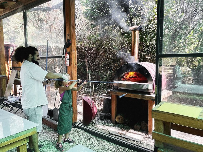 A kid putting a pizza into an oven at a cooking class in Rome