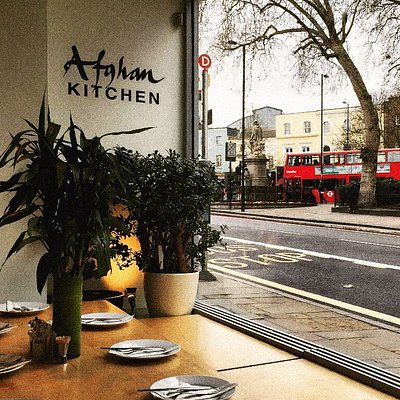 Blick auf London aus dem Fenster des Restaurants Afghan Kitchen mit zwei Pflanzen und einem gedeckten Tisch
