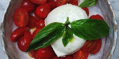 Teller mit Kirschtomaten, Käse und Basilikum auf einer Marmorplatte im Campania