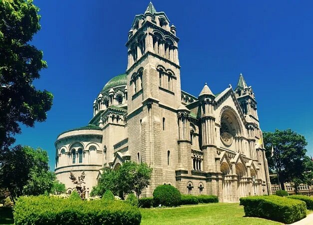 Exterior of stone Cathedral Basilica of Saint Louis with green lawn