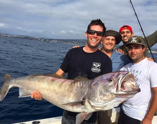 Adult holding up large fish with three other people behind them