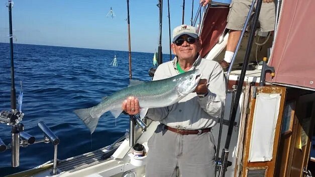 Older person holding up fish on a boat