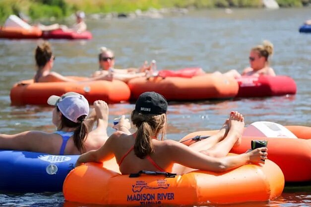Several people in orange tubs floating on river