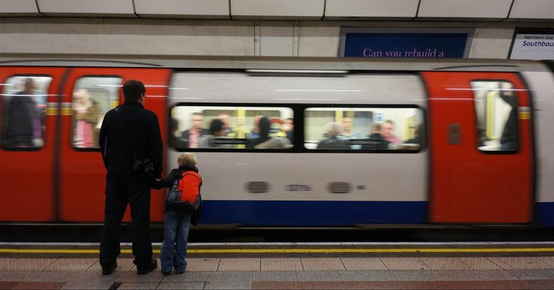 ロンドン地下鉄のホームで電車を待つ父親と息子