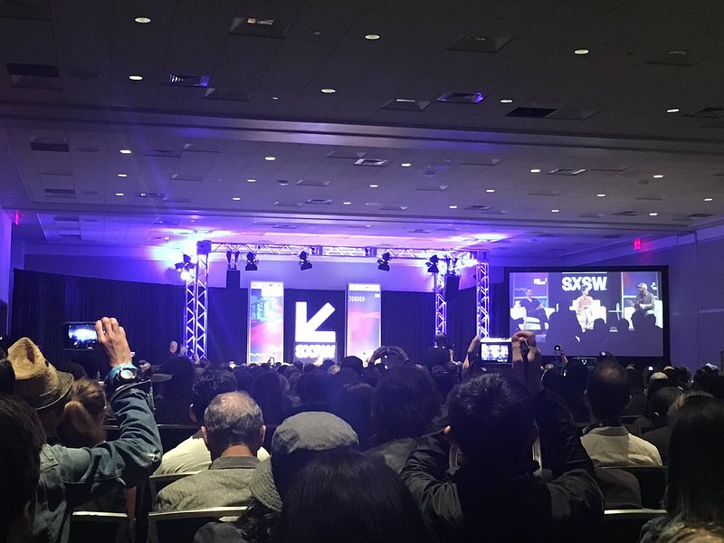 A crowd looks upon a purple-lit stage at South by Southwest