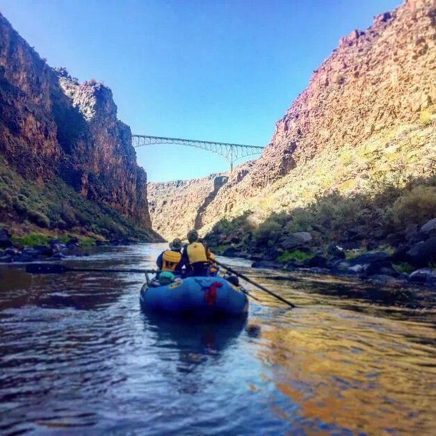 People on raft rowing through canyon