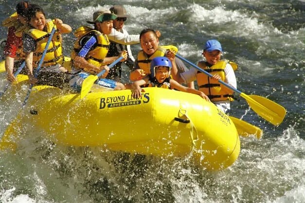 Adults and children in yellow raft on rapids