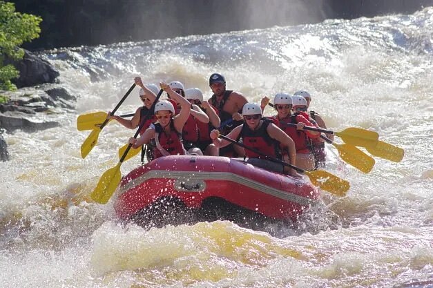 People in red raft rowing yellow oars