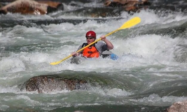 One person in single raft rowing amid rapids