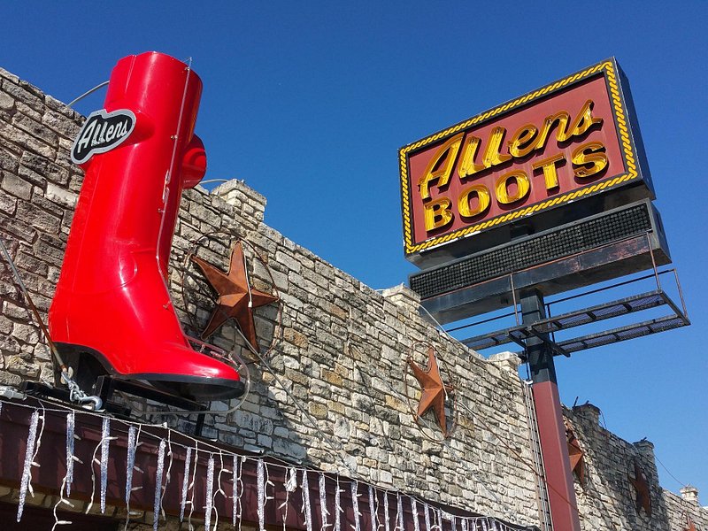Large red boot on the front of the top of a building, with a sign reading "Allens Boots"