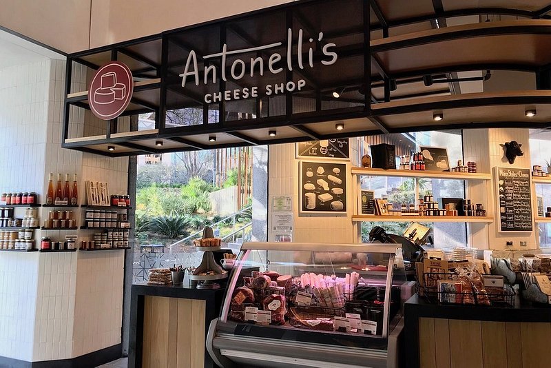 A sign at the top of the picture reads "Antonelli's Cheese Shop," and a deli-style glass window is below with meats and cheeses, and several other items for purchase dot the rest of the photo