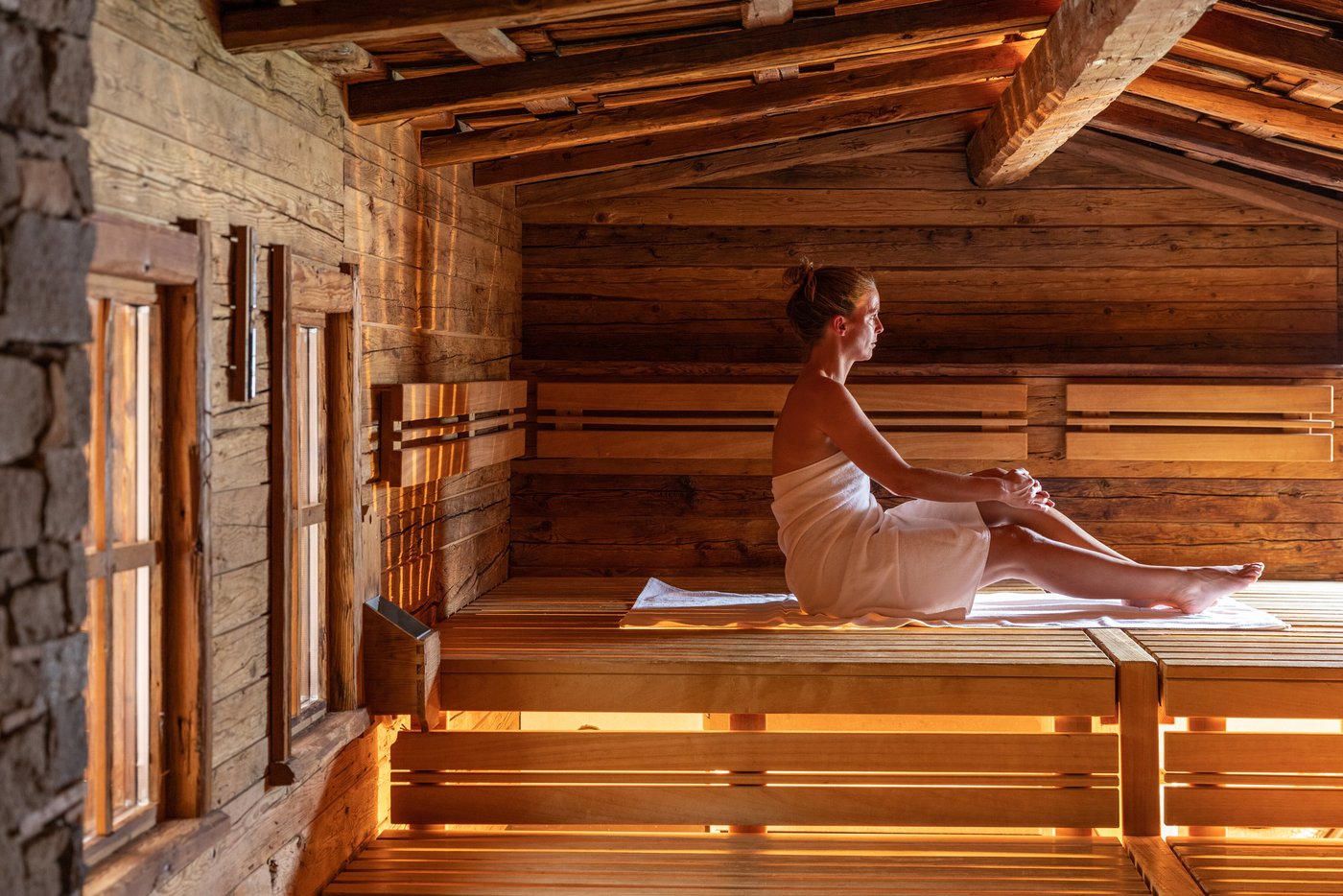 Moderner Saunabereich im Leading Family Hotel & Resort Alpenrose mit Holzbänken, angenehmer Beleuchtung und Panoramafenster