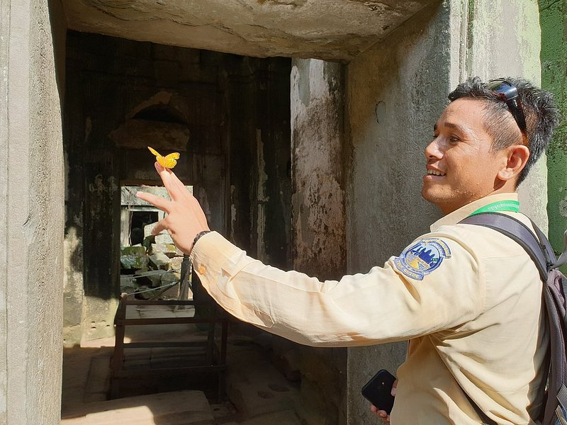 A tour guide in Angkor Wat with a butterfly on his hand
