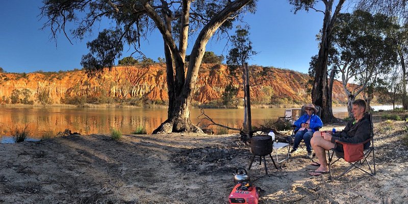 A panorama of two campers sitting by a rustic stove on the banks of the Murray River