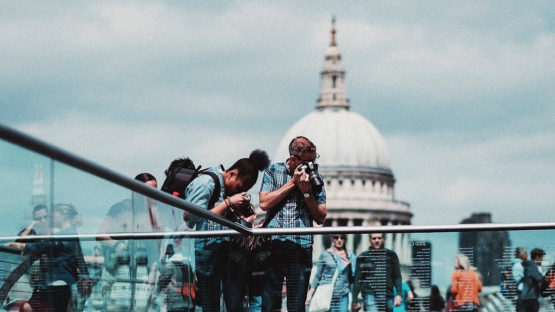 A pair of travelers taking photos on the Millennium Bridge