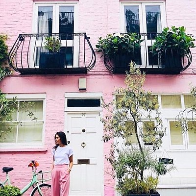 A woman posing in front of a pink house along Notting Hill