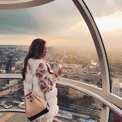 A woman with a champagne glass in the London Eye at sunset