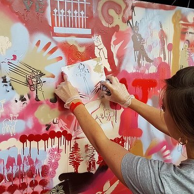 An artist spray painting on a wall in Shoreditch