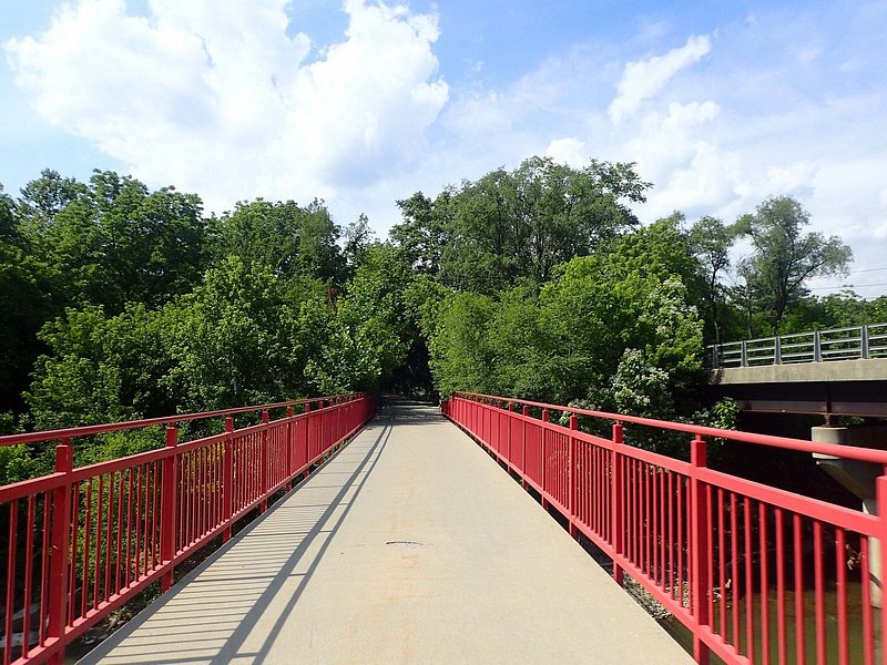 A light-colored paved path narrows into the distance, flagged by bright red railings