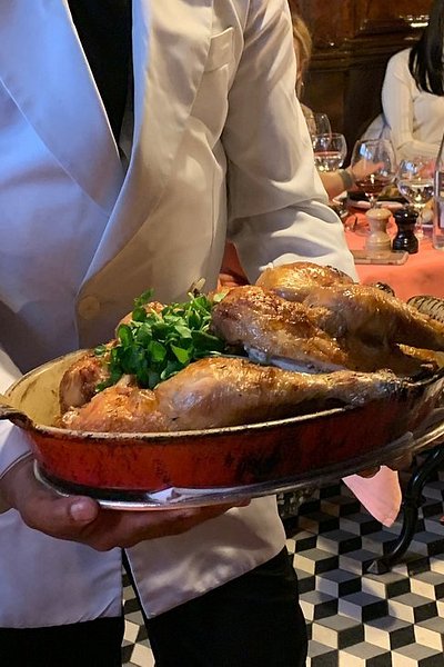 A server bringing out a roast chicken at L’Ami Louis bistro in Paris