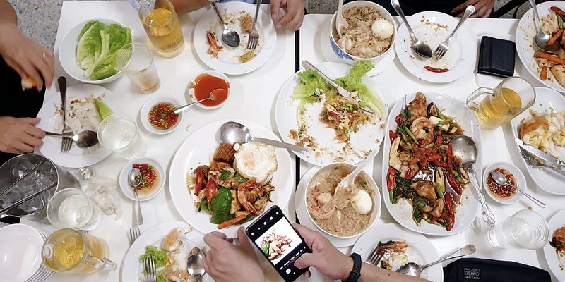 Friends eat around a table filled with delicious thai dishes