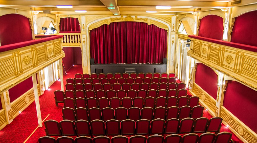 La salle de Théâtre 100 Noms vue du balcon, avec sa scène et ses rideaux imposants