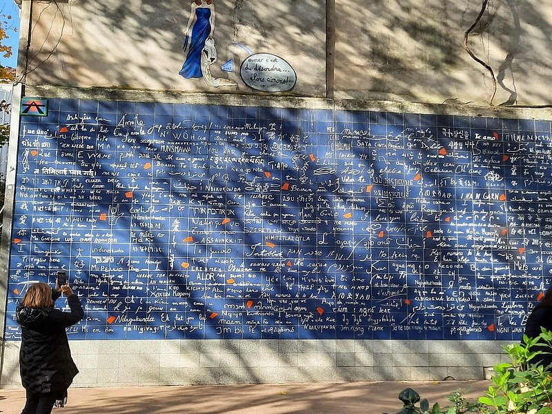 A woman taking a photo of the Le Mur des Je t'aime wall in Paris