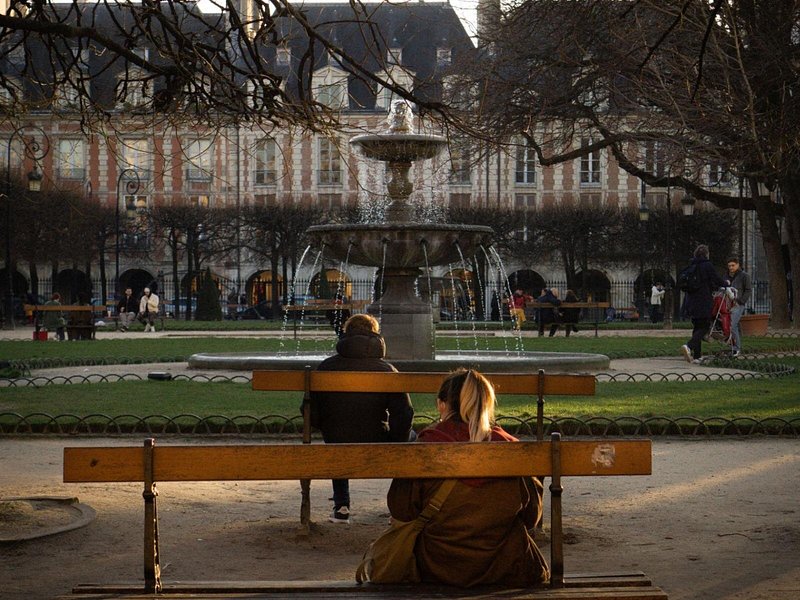 People sitting on benches at the Place des Vosges in Paris
