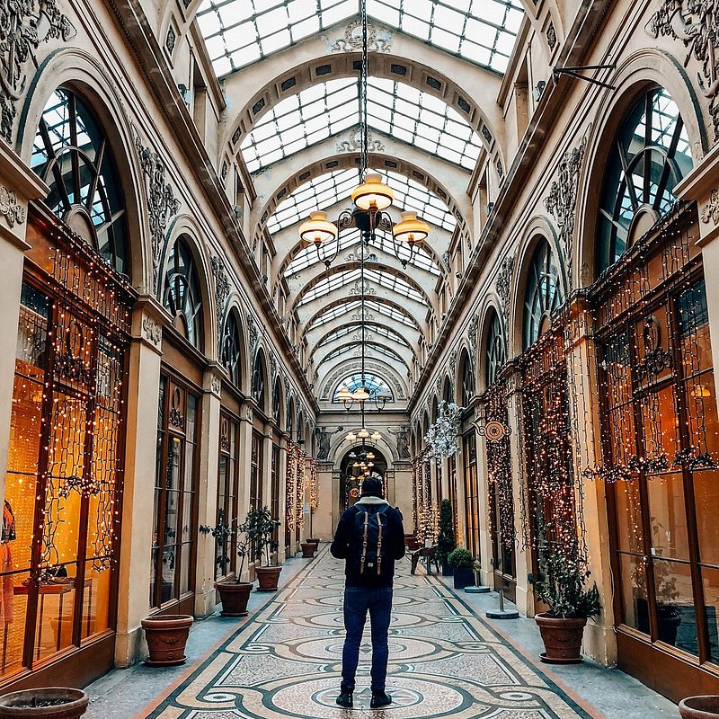 A man standing  in the middle of a corridor at Galerie Vivienne in Paris