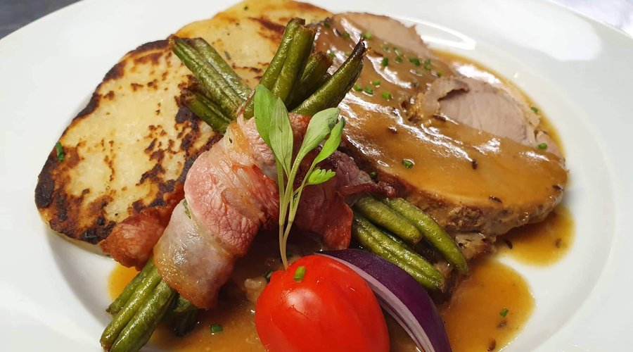 Smoked and baked slices of pork leg with roasted potato dumplings and green beans in bacon. 
