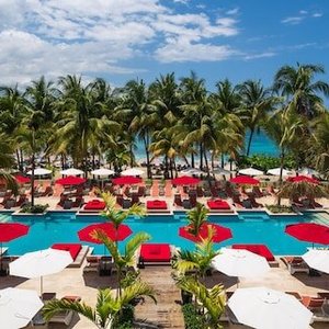Pool next to the beach with cabanas and pool chairs