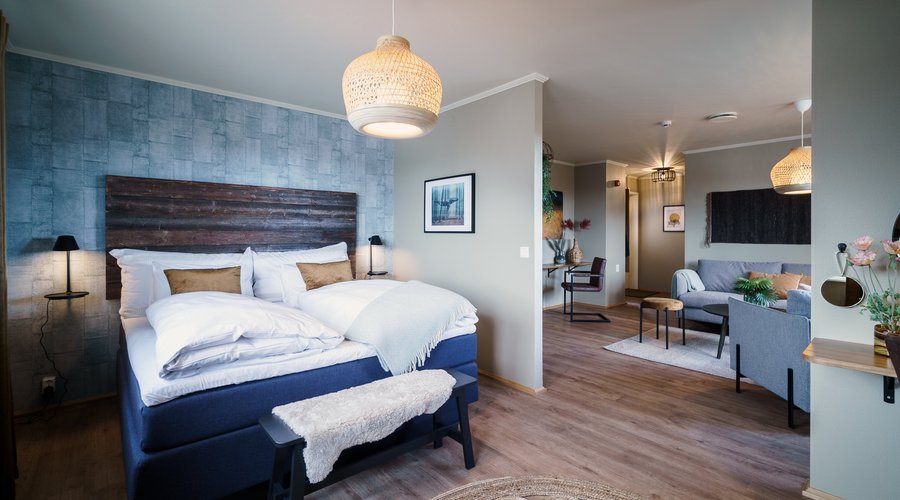 Soverom og stue i vår Suite. Queen size bed, sminkebord/speil, sofakrok med tv, balkong og sjøutsikt