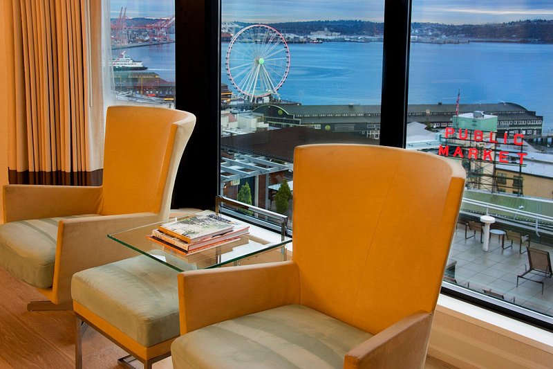 Two tan chairs sit in front of a window, where the Great Wheel and Pike Place Market sign are visible