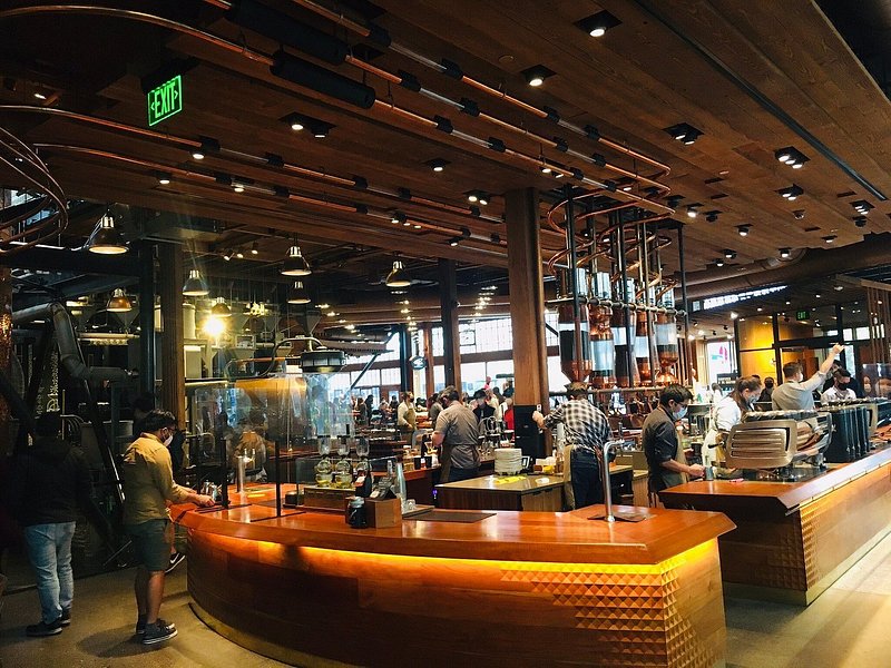 Warm light illuminates a coffee bar full of workers and customers alike