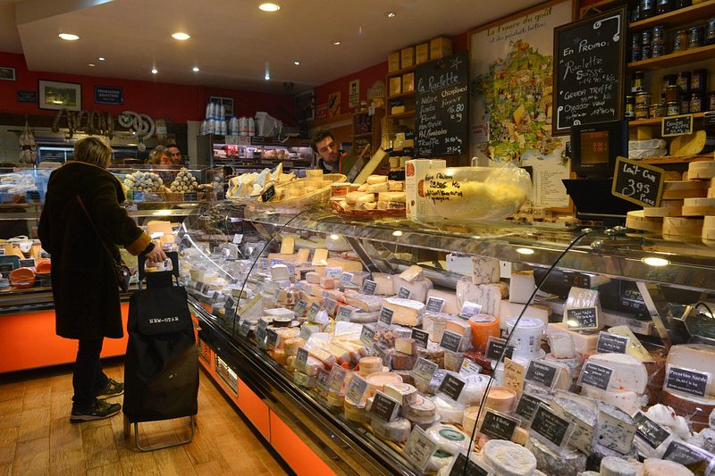 A woman with a black trolley in La Fermette looking at cheese in Paris