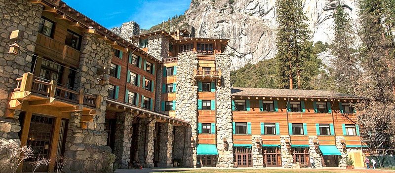 Exterior of stone and wood hotel in front of mountains