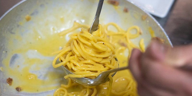 Spaghetti carbonara being twirled on a ladle
