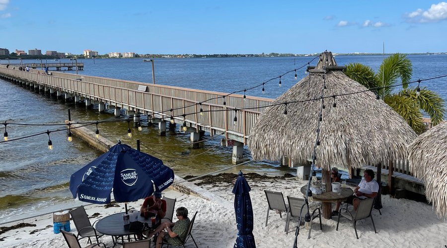 Sandy beach and tiki hut tables at The Boathouse