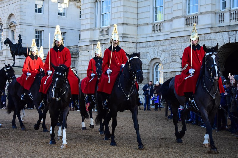 Des gardes habillés en rouge vif, montant à cheval devant Buckingham Palace, à Londres