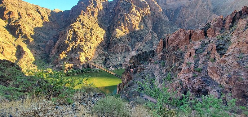 A bridge between canyon walls over a green river