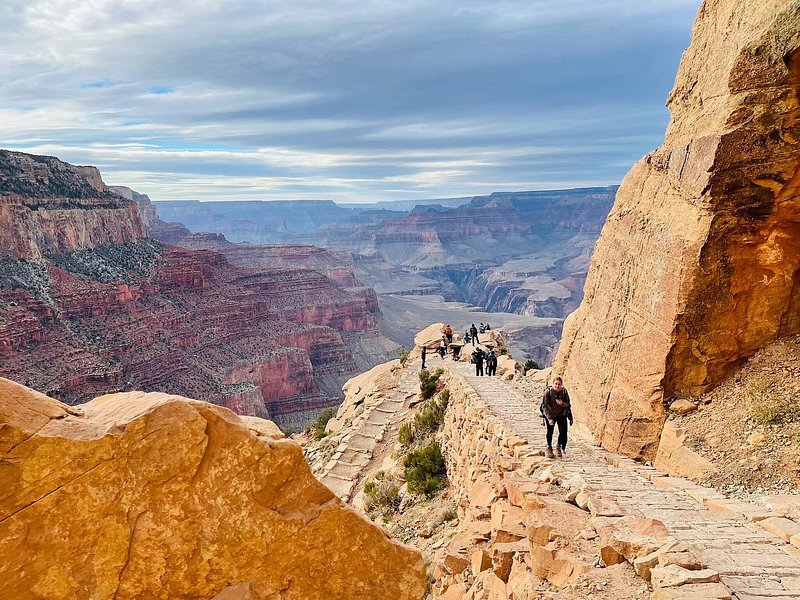 Several people take in the view from a sandstone path above the canyon