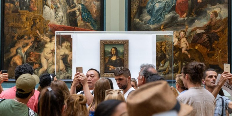 A crowd of visitors in the Louvre Museum in front of the Mona Lisa in Paris.